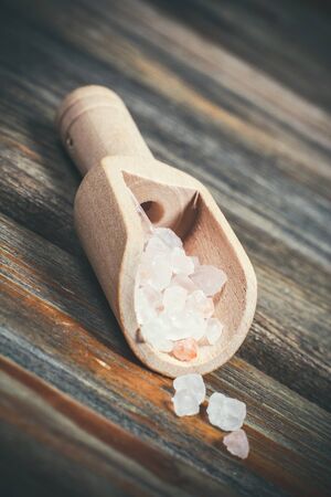 Different spices and salt lie in wooden spoons on a wooden brown tableの写真素材
