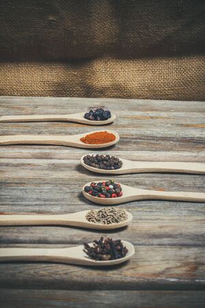 Different spices and salt lie in wooden spoons on a wooden brown tableの写真素材