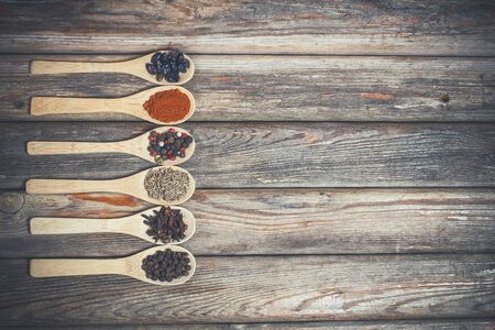 Different spices and salt lie in wooden spoons on a wooden brown tableの写真素材