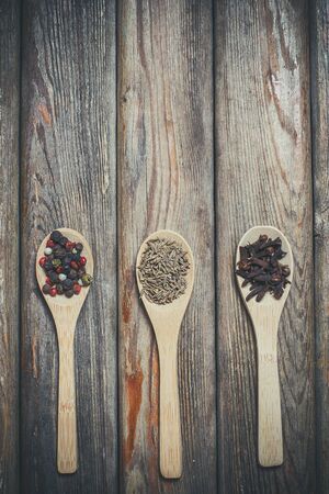 Different spices and salt lie in wooden spoons on a wooden brown tableの写真素材