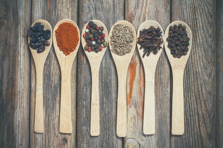 Different spices and salt lie in wooden spoons on a wooden brown tableの写真素材