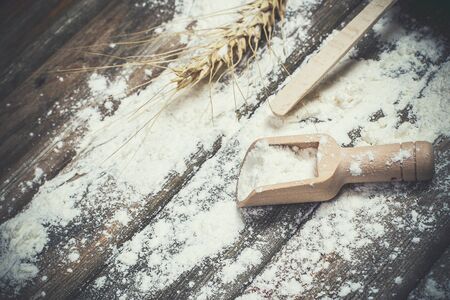 Flour and spikelets of wheat for baking bread lies on a wooden brown surfaceの写真素材
