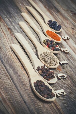 Different spices and salt lie in wooden spoons on a wooden brown tableの写真素材