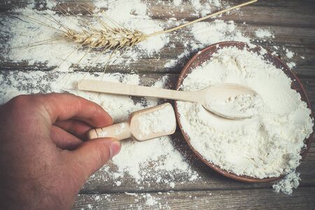 Flour and spikelets of wheat for baking bread lies on a wooden brown surfaceの写真素材