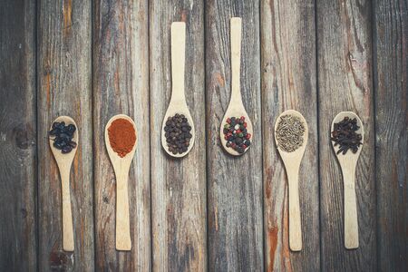 Different spices and salt lie in wooden spoons on a wooden brown tableの写真素材