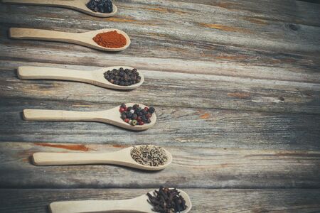 Different spices and salt lie in wooden spoons on a wooden brown tableの写真素材