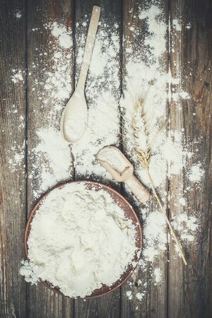 Flour and spikelets of wheat for baking bread lies on a wooden brown surfaceの写真素材