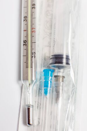 Thermometer for measuring temperature and an injection syringe on a white background