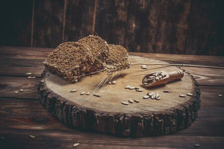 Fragrant black bread with spices, grains and ears of wheat on a wooden vintage surface