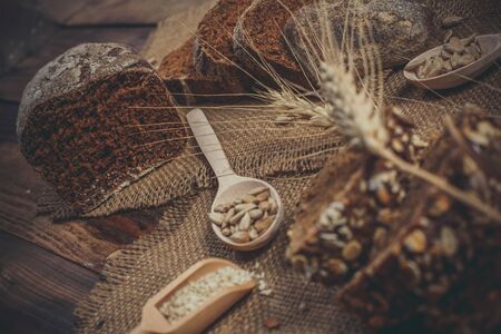Fragrant black bread with spices, grains and ears of wheat on a wooden vintage surfaceの写真素材