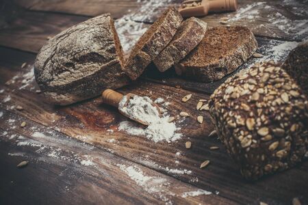 Fragrant black bread with spices, grains and ears of wheat on a wooden vintage surface