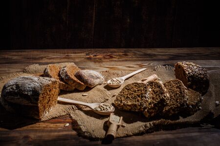 Fragrant black bread with spices, grains and ears of wheat on a wooden vintage surfaceの写真素材