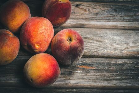 Ripe tasty peaches on a wooden brown surface in vintage style.の写真素材