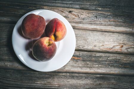 Ripe tasty peaches on a wooden brown surface in vintage style.の写真素材