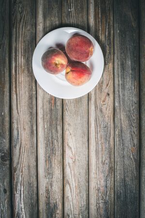 Ripe tasty peaches on a wooden brown surface in vintage style.の写真素材