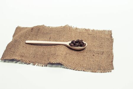 Fragrant coffee grains in light wooden spoons on a white backgroundの写真素材