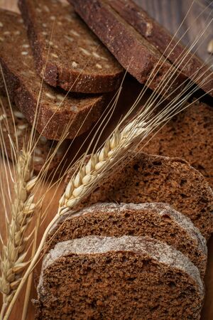 Different buns of fresh bread and spikelets of wheat on a vintage background