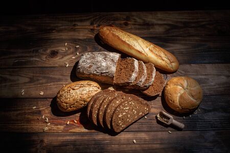 Different buns of fresh bread and spikelets of wheat on a vintage backgroundの写真素材