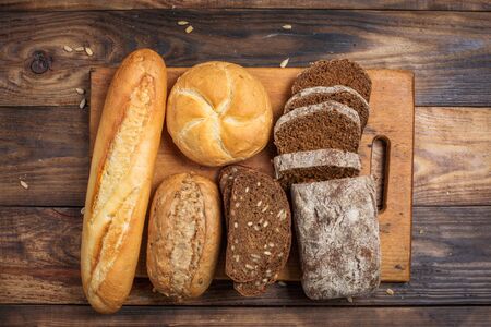 Different buns of fresh bread and spikelets of wheat on a vintage backgroundの写真素材