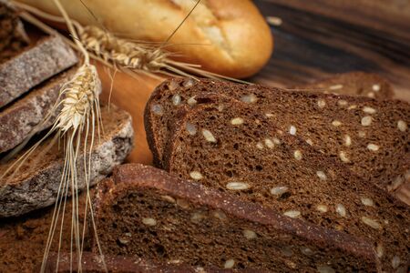 Different buns of fresh bread and spikelets of wheat on a vintage background