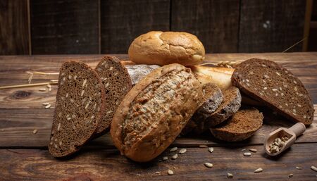 Different buns of fresh bread and spikelets of wheat on a vintage background