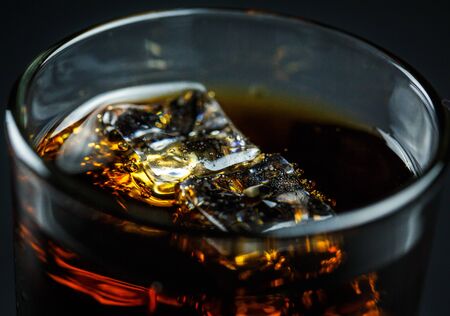 Soda in a glass on a black background with ice cubes and drops closeの写真素材