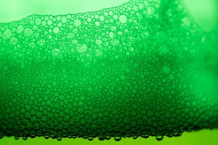 Beer with bubbles and foam in a green bottle