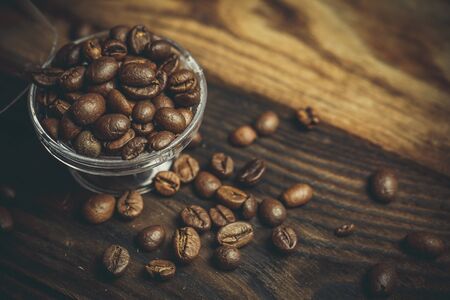 A lot of fragrant coffee beans on a plastic stand on a wooden table