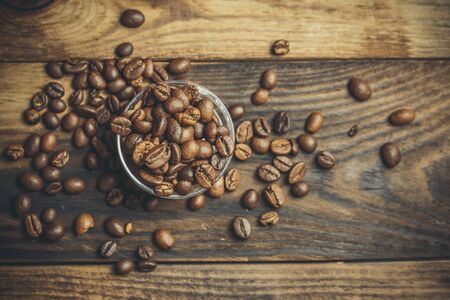 A lot of fragrant coffee beans on a plastic stand on a wooden tableの写真素材