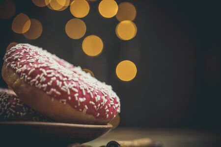 Tasty pink donuts with sweet topping on a wooden tableの写真素材