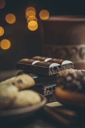 Delicious donuts with chocolate and a cup of coffee in warm colors.
