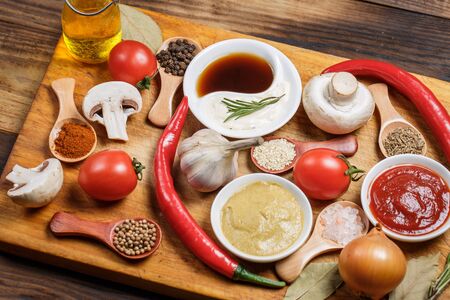 A lot of different spices, vegetables and ingredients for cooking on a wooden background