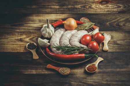 Many different spices, vegetables and ingredients, and fresh raw barbecue sausages for the family.の写真素材