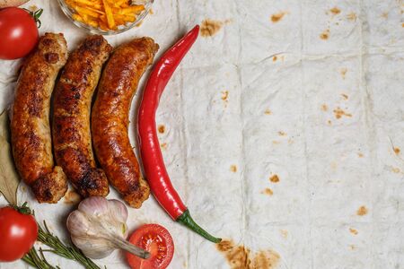 Fried sausages, vegetables, hot peppers and various spices and ingredients on pita breadの写真素材