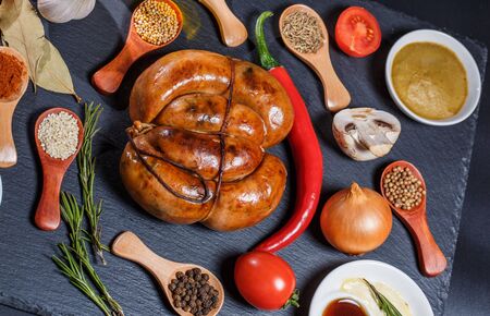 Grilled sausages, vegetables, hot peppers and various spices and ingredients on a black backgroundの写真素材