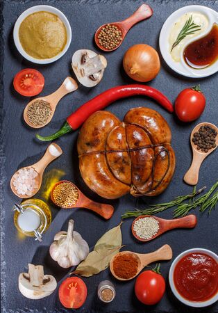Grilled sausages, vegetables, hot peppers and various spices and ingredients on a black backgroundの写真素材