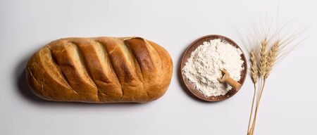 Tasty fresh black and white bread with wheat and flour on a white background