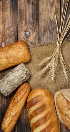 Different loaves of tasty bread with wheat, flour and gluten on a wooden tableの写真素材