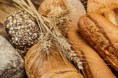 Different loaves of tasty bread with wheat, flour and gluten on a wooden table