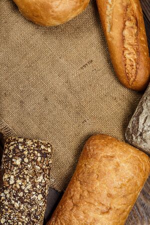 Different loaves of tasty bread with wheat, flour and gluten on a wooden table