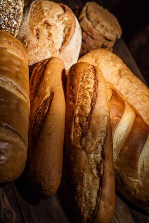 Different loaves of tasty bread with wheat, flour and gluten on a wooden tableの写真素材