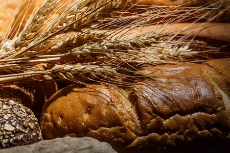 Different loaves of tasty bread with wheat, flour and gluten on a wooden table