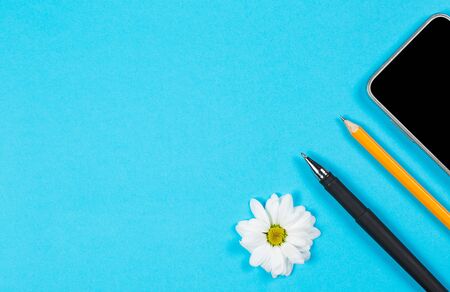 Different office supplies and tablet with a phone for work and education on a blue backgroundの写真素材