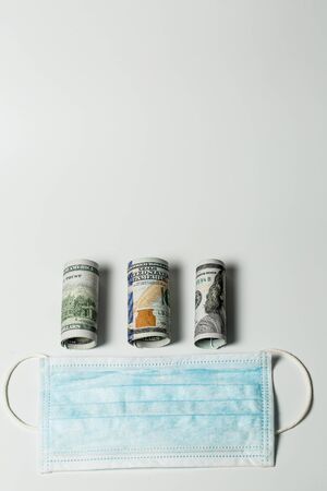 Medical mask from virus infection during a pandemic and quarantine with big money as a sign of the cost of healthの写真素材