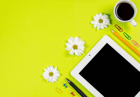 Various stationery and tablet with a phone for work and study and a cup of coffee on a green backgroundの写真素材