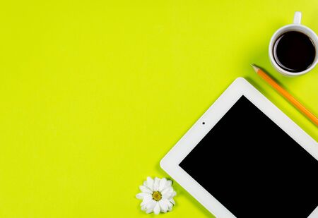 Various stationery and tablet with a phone for work and study and a cup of coffee on a green backgroundの写真素材