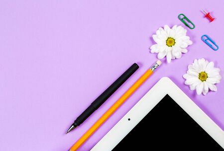 Various stationery and tablet with a phone for work and study and a cup of coffee on a purple...