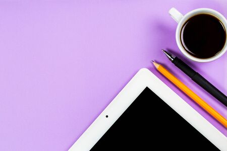 Various stationery and tablet with a phone for work and study and a cup of coffee on a purple backgroundの写真素材