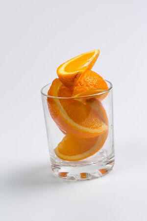 Fresh oranges in a glass cup on a white backgroundの写真素材