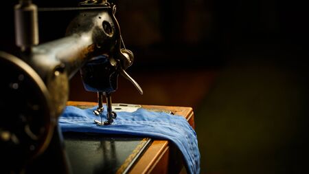 Old sewing machine, the man who sews on it, in dark colorsの写真素材